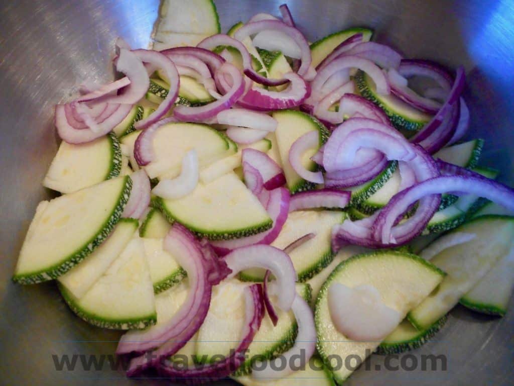 Thinly sliced zucchini and onions in a bowl